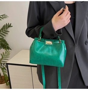 Detail of emerald green PU leather bag featuring vintage texture and gold twist lock closure