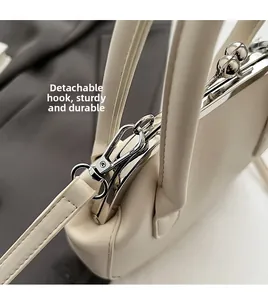 Detail of cream leather handbag showing sturdy detachable silver hooks and vintage metal clasp