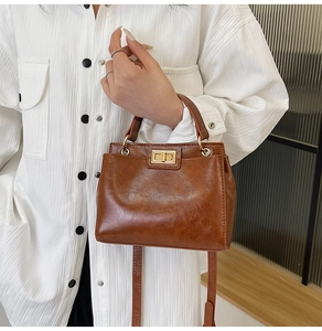 Detailed shot of retro brown leather handbag with gold twist lock and shoulder strap