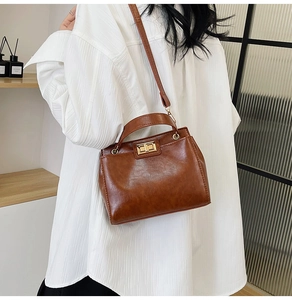 Detail of vintage brown shoulder bag with golden twist lock on a white shirt model