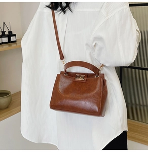 Brown vintage faux leather handbag with gold twist lock shown on a female model