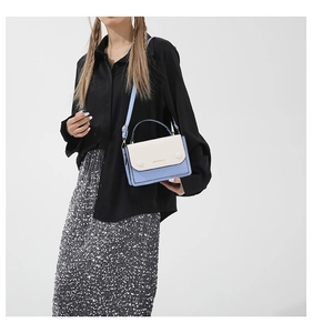 Detail of light blue and cream contrast handbag worn with elegant sequin skirt