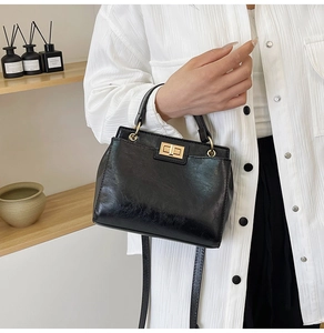 Close-up of vintage black handbag featuring textured leather and gold square twist lock