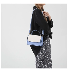 Detail of color-block crossbody bag featuring light blue faux leather and gold lettering