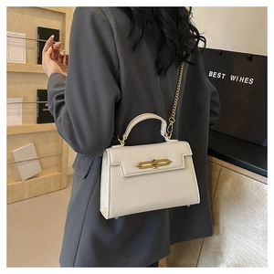 Detalle de bolso blanco en piel granulada con hebilla dorada y correa de cadena