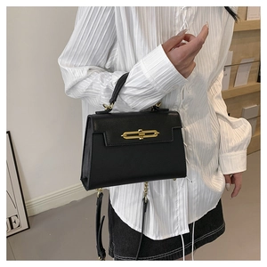 Detalle de bolso trapecio negro con grano cruzado y cierre metálico dorado con correa