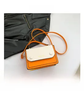 Detailed view of two-tone orange and cream crossbody bag with contrast buckle accents