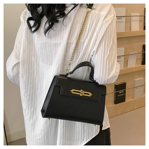 Detalle de bolso en cuero negro texturizado con cadena dorada y cierre de metal fino