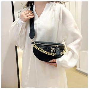 Détail d'un sac de poitrine noir avec chaîne dorée et texture tissée sur un mannequin femme
