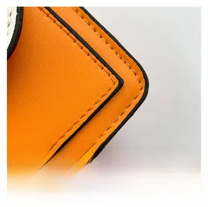 Detailed macro view of orange textured leather bag with black edge painting and stitching