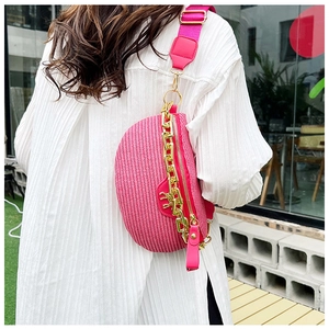 Détail du sac dumpling tissé rose avec grosse chaîne dorée et large bandoulière