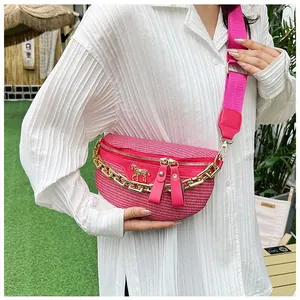 Détail du sac bandoulière tissé fuchsia avec chaîne dorée et boucle de cheval en métal