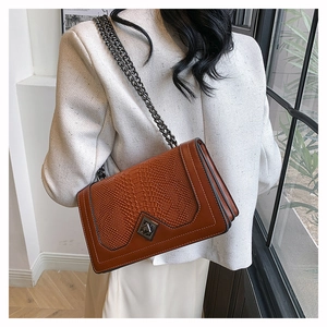 Brown crocodile pattern chain bag with metallic diamond-shaped lock on a female model