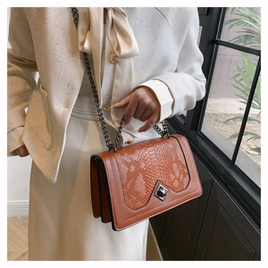 Close-up of brown crocodile texture flap bag with silver metal chain and geometric lock