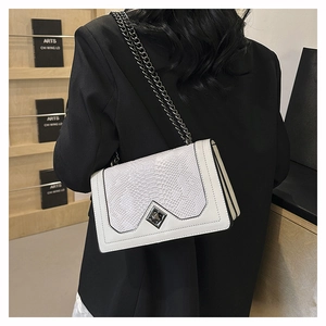 Detail of white crocodile embossed flap bag with metal chain strap and twist-lock buckle