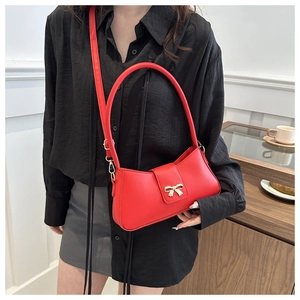 Détail du sac bandoulière rouge en similicuir avec boucle dorée en forme de nœud chic