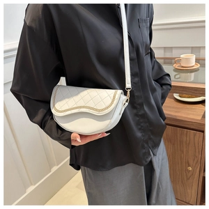 Detalle de bolso de montura blanco acolchado con cadena dorada usado por modelo