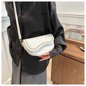 Detalle del bolso de silla blanco acolchado con cadena dorada y textura de cuero refinado