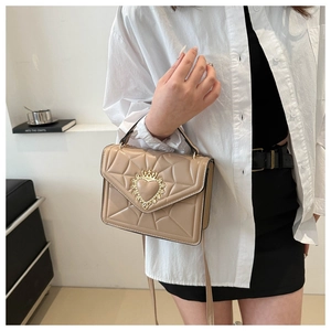 Detail of beige quilted leather bag with golden heart-shaped crown clasp and chain strap