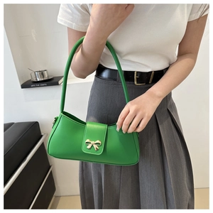 Détail d'un sac sous le bras en cuir vert vif avec un fermoir nœud doré élégant