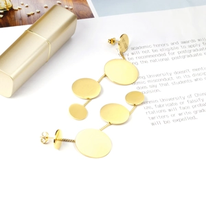 Macro detail of golden geometric dangling earrings with four tiered round metal discs