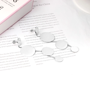 Close-up of silver steel tassel earrings with four round discs on a magazine page
