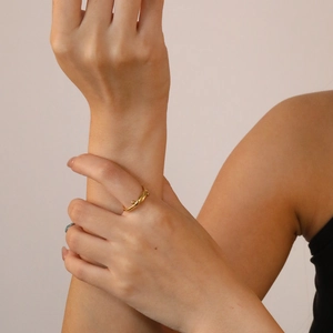 Detail of minimalist 18K gold plated twisted ring worn on a finger for a chic look