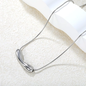 Collier minimaliste à pendentif irrégulier poli sur fond de pierre blanche texturée