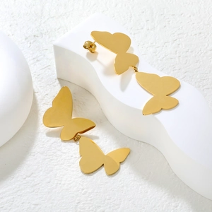 Gros plan de boucles d'oreilles papillon dorées avec design double papillon sur support blanc