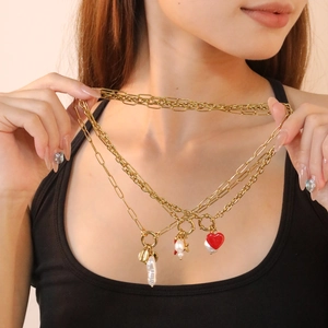 Gold multi-layered necklace with red heart pendant and white pearls on a model