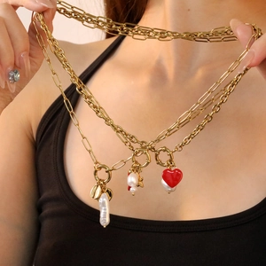 Gold layered necklace with baroque pearl, red heart pendant and shell on model
