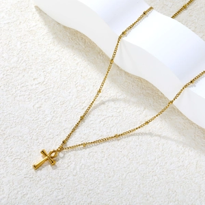 Elegant gold Ankh cross pendant necklace with small beads on a minimalist white surface