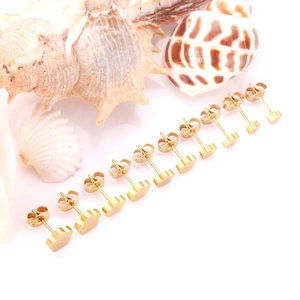 Dettaglio di dieci orecchini a fiore in acciaio inossidabile dorato su sfondo di conchiglia