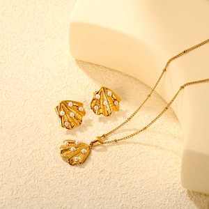 Golden seashell and pearl jewelry set with stud earrings and necklace on beige background