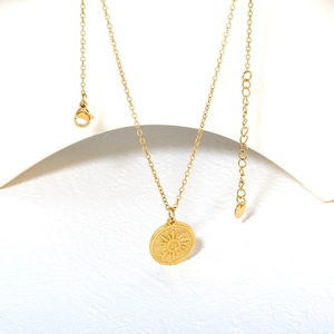 Minimalist stainless steel gold sunburst pendant necklace with adjustable chain on white stand