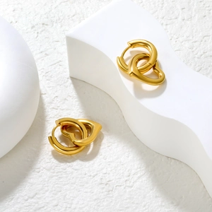 Macro shot of polished gold heart earrings on a minimalist white display stand
