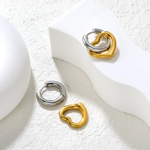 Detailed macro shot of interlocking silver circle and golden heart earrings on white stone