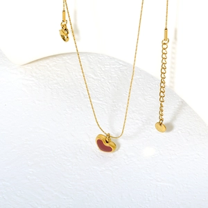 Gold stainless steel cross heart necklace with red enamel pendant on white marble
