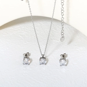 Silver jewelry set with necklace and four-claw zircon earrings on a white stone base