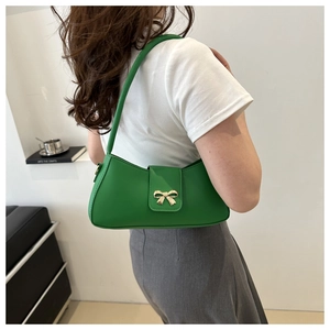 Détail d'un sac baguette vert en cuir PU avec une boucle en métal dorée en forme de nœud