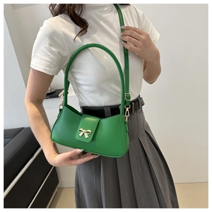 Modèle portant un sac bandoulière vert demi-lune avec boucle nœud doré et poignée fixe