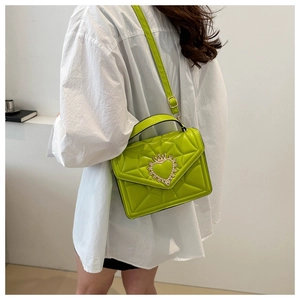 Lime green quilted leather handbag with gold heart crown buckle worn by a model