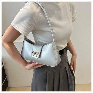 Close-up of a silver underarm bag featuring a metallic gold bow clasp and sleek PU finish