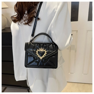 Detail view of black quilted leather shoulder bag with gold crown heart metal buckle