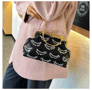Detail of black sequin evening clutch bag with gold chain strap held by a model