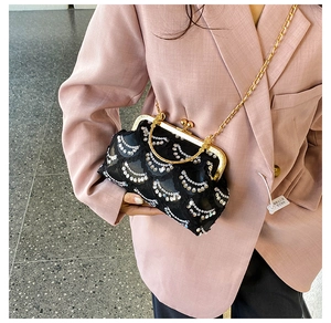 Detail of black lace and sequin evening bag with gold chain strap on pink blazer
