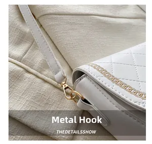 Detalle de bolso silla acolchado blanco con gancho de metal dorado y bordado