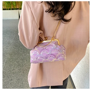 Detail view of purple sequin evening clutch bag with gold chain on model in purple suit