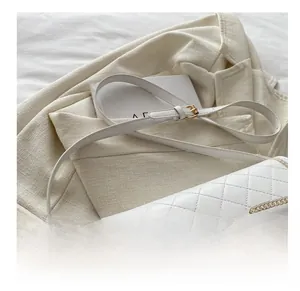 Primer plano de bolso silla acolchado blanco con cadena dorada sobre una chaqueta con textura