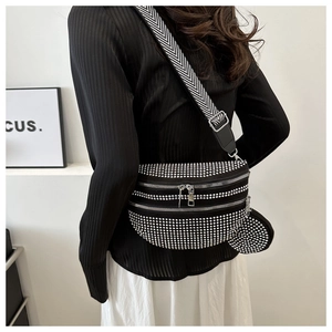 Detail der schwarzen Strass-Brusttasche mit Nieten und weitem Chevron-Gurt